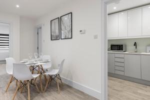 a white kitchen and dining room with a table and chairs at Star London Vivian Avenue 2-Bed Haven in The Hyde
