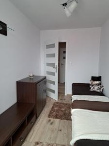 a bedroom with a bed and a dresser and a door at APARTAMENT na STARÓWCE in Pasłęk