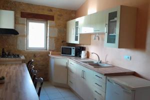 cocina con armarios blancos, fregadero y ventana en Gite LOT'ivier Piscine et Lot 2 à 4 pers, en Montayral