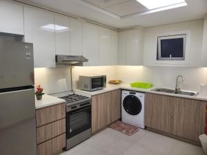 a kitchen with a stove and a washer and dryer at FULLY FURNISHED 2BR APARTMENT WITH MAIDS ROOM B411 in Dubai