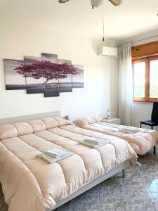 duas camas num quarto com três pinturas na parede em B&B Casa degli Ulivi em Nettuno