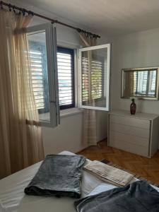 a bedroom with a bed and two windows and a dresser at Apartment Ivanka in Senj