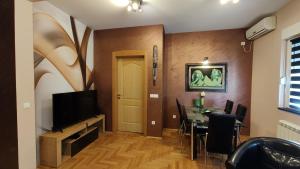 ein Esszimmer mit einem Esstisch und einem TV in der Unterkunft Apartment StefanA in Belgrad