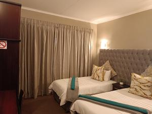a hotel room with two beds and a window at Apartment A8 inside Bains Lodge in Bloemfontein