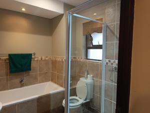 La salle de bains est pourvue de toilettes, d'une baignoire et d'une douche. dans l'établissement Apartment A8 inside Bains Lodge, à Bloemfontein
