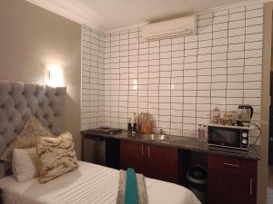 een kamer met een bed en een magnetron op een aanrecht bij Apartment A8 inside Bains Lodge in Bloemfontein