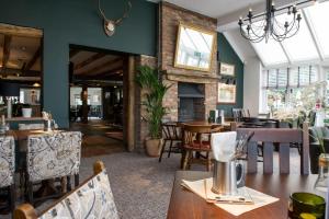 restauracja ze stołami i krzesłami oraz kominkiem w obiekcie The Melville Inn by Innkeeper's Collection w mieście Dalkeith