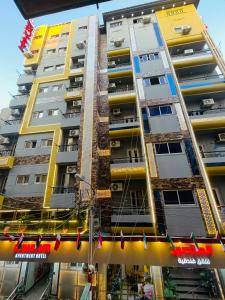 ein hohes gelbes Gebäude mit Flaggen davor in der Unterkunft El mansour hotel apartmen 81 in Mansoura