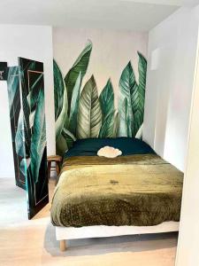 a bedroom with a bed with a mural of leaves at Le p’tit nid des Halles in Le Grand-Lemps