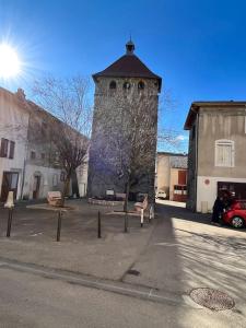 a building with a tower in the middle of a street at Le p’tit nid des Halles in Le Grand-Lemps