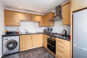 a kitchen with wooden cabinets and a washer and dryer at Stunning 3BD Home Hillsborough Sheffield in Sheffield