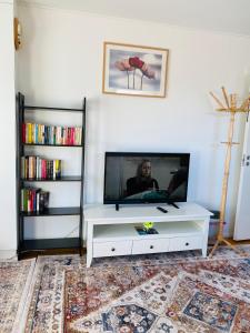 a living room with a tv and a white entertainment center at two bedrooms,dining area and bathroom with private entrance in Kotka
