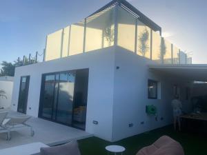 une grande maison blanche avec des portes en verre. dans l'établissement Cap-Canaria FKK, à San Bartolomé