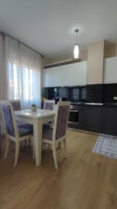 Tirana New Bazaar- Apartment no-1 في تيرانا: مطبخ مع طاولة بيضاء وكراسي في مطبخ