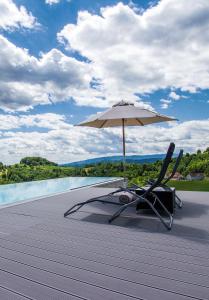 a chair and an umbrella on a wooden deck at *BRANDNEW* MODERNES APARTMENT IN DEN WEINBERGEN MIT POOL UND SAUNA in Spielfeld