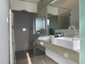 bagno con lavandino e grande specchio di *BRANDNEW* MODERNES APARTMENT IN DEN WEINBERGEN MIT POOL UND SAUNA a Spielfeld