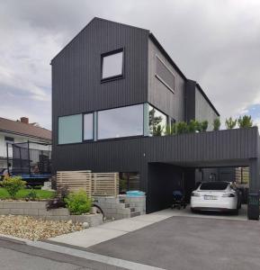 a black house with a car parked in front of it at Modern and comfortable apartment in attractive neighborhood in Stavanger