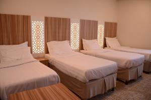 a hotel room with three beds and two windows at Artal Taiba Hotel in Al Madinah