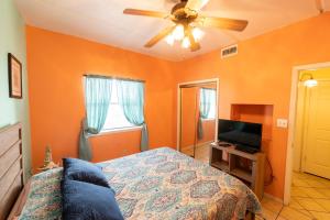 een slaapkamer met oranje muren, een bed en een plafondventilator bij South Padre Island condo is walking distance to the beach, Sleeps 6, Third Floor, 2024 Traveler Award in South Padre Island