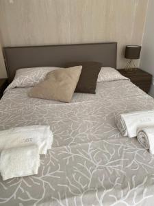 1 cama con 2 almohadas y toallas en Il Giardino sul mare, en Acireale