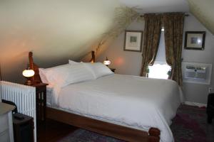 a bedroom with a white bed and a window at Cooperstown Bed and Breakfast in Cooperstown
