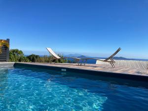 a pool with two chairs and the ocean in the background at COROSSOL in Trois-Rivières