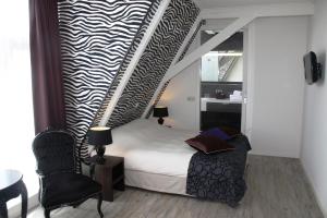 a small bedroom with a bed and a chair at Hotel Zeezicht in Harlingen