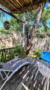 eine Terrasse mit einem Stuhl, einer Schaukel und einem Baum in der Unterkunft Chiibal in Tulum