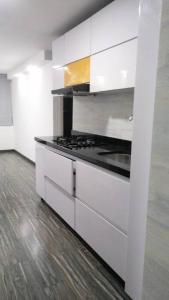 a kitchen with white cabinets and a stove top oven at Apartamento embajada americana in Bogotá