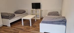 a room with two beds and a table and a tv at Fair apartment 2 in Kelsterbach +4 photos