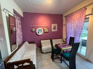 um quarto com uma mesa e cadeiras e uma parede roxa em Villa Leonidas KOUTSOUPIA em Kókkinon Nerón