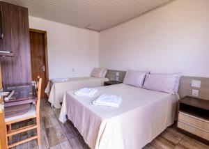 a hotel room with two beds with white sheets at Hotel Alegrete in Alegrete