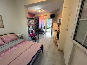 um quarto com uma cama rosa e uma cozinha em Villa Leonidas KOUTSOUPIA em Kókkinon Nerón
