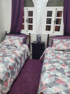 a bedroom with two beds and two windows at Modern fully equipped two story appartement/duplex in Safi