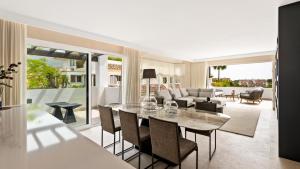 Luxury apartment at Monte Paraiso في مربلة: غرفة معيشة مع طاولة وكراسي زجاجية