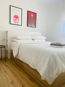 ベニドルムにあるApartamentos Carrの白いベッド1台、壁に2枚の写真が飾られたベッドルーム1室