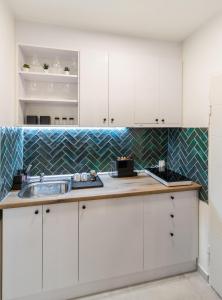 a kitchen with white cabinets and a sink at Harmony apartman in Donji Milanovac