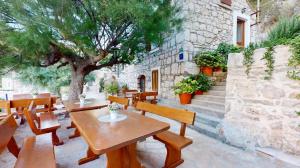 a patio with wooden tables and benches and a tree at Apartmani Bepin in Selca kod Bogomolja