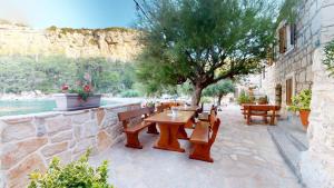a patio with a table and benches and a tree at Apartmani Bepin in Selca kod Bogomolja