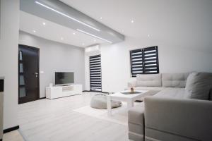 uma sala de estar branca com um sofá e uma televisão em Apartman Amina em Mostar