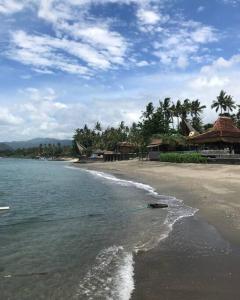 a beach with a boat in the water at Spacious Private Pool Apartment-Beachside Resort in Candidasa