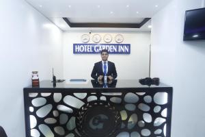 a man in a suit and tie standing at a desk at Hotel Garden Inn in Sylhet