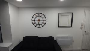 a black couch in a room with a clock on the wall at Apartment in St Denys in Southampton