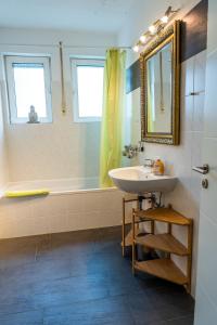 ein Badezimmer mit einem Waschbecken, einer Badewanne und einem Spiegel in der Unterkunft Art City Studio Kassel 7 in Kassel
