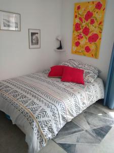 Un dormitorio con una cama con almohadas rojas y una pintura en studio proche des cures, en Lamalou-les-Bains