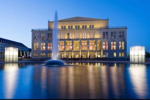 un grand bâtiment avec une fontaine devant lui dans l'établissement Apartment Leipzig Zentrum mit Tiefgarage, à Leipzig