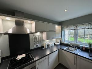 uma cozinha com armários brancos e um balcão preto em Newt's Place em Filey