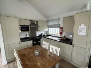a kitchen with a wooden table and a kitchen with white cabinets at Sandy Bay Hideaway - Part of the The Bay Filey Holiday Village with pool, gym and direct beach access, pub, restaurant, tennis and meadows walks in Filey +36 photos