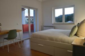 a bedroom with a bed and a desk and two windows at Casa da Várzea - O Castelo à Janela!!! in Óbidos