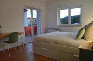1 Schlafzimmer mit einem Bett, einem Schreibtisch und 2 Fenstern in der Unterkunft Casa da Várzea - O Castelo à Janela!!! in Óbidos